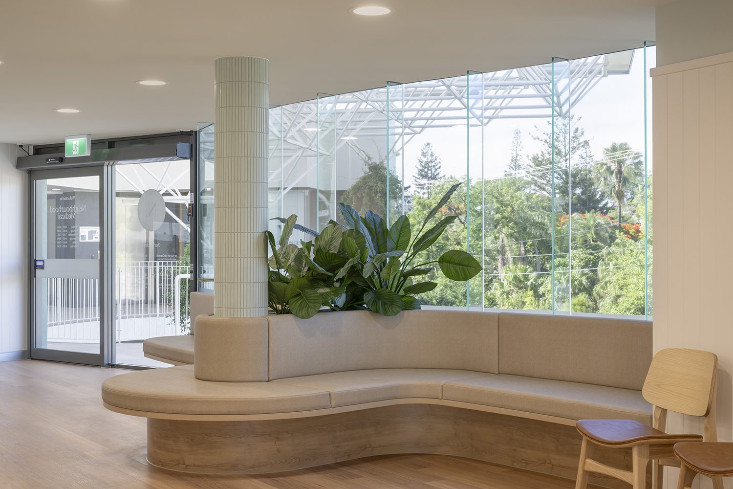 Entry area with a curved bench seat wrapping a planter, full height glazing and a timber floor